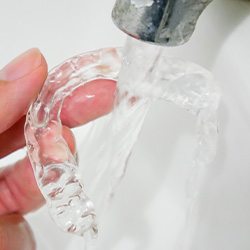 Person cleaning their Invisalign with lukewarm water