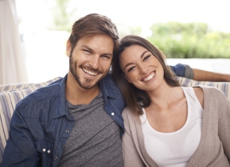 Smiling man and woman sitting next to each other on couch