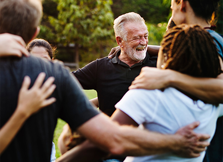 Group of people forming circle with arms around each others shoulders