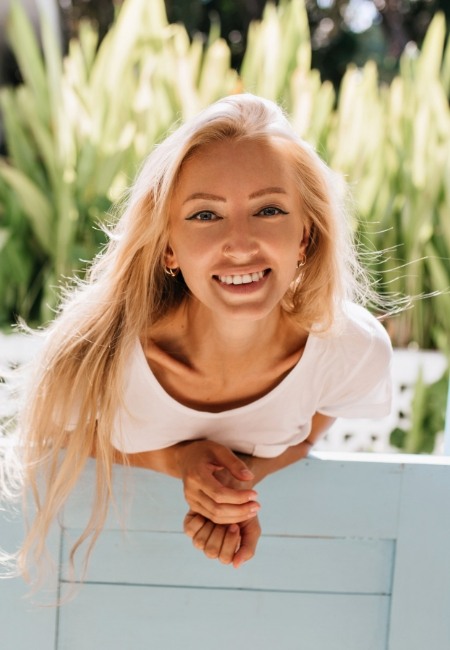 Blonde woman smiling outdoors after cosmetic dentistry in Sachse