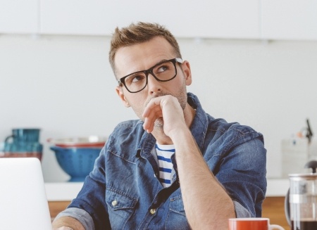 Man sitting at desk covering his mouth with his hand