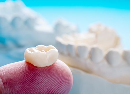 Dental crown resting on finger