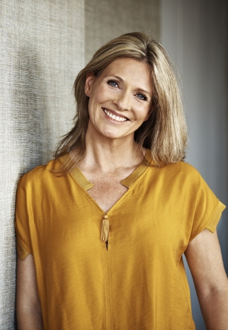 Woman in yellow blouse smiling with dental implants in Sachse