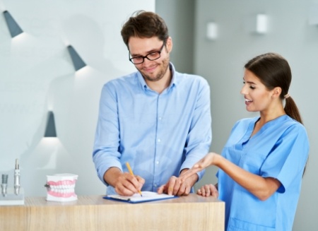 Dental team member showing a patient where to sign on clipboard