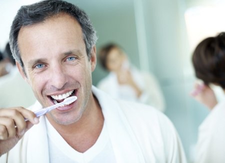 Man smiling while brushing his teeth