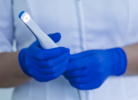 Dentist holding a thin white intraoral camera