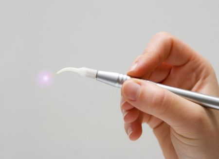 Hand holding a thin gray soft tissue laser device