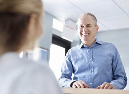 Man smiling at dental office receptionist