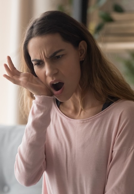 Woman holding mouth in pain before emergency dentistry in Sachse