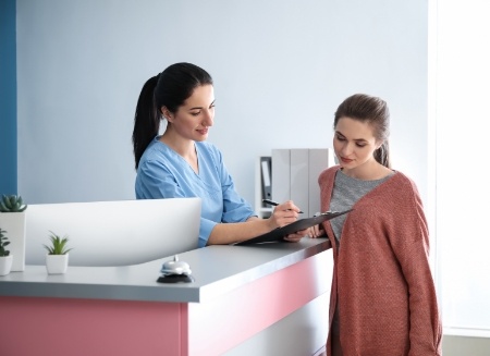 Dental team member showing a patient where to sign on clipboard