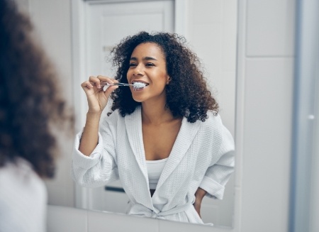 Woman smiling while brushing her teeth