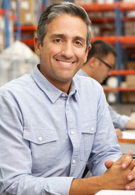 Man in light blue shirt smiling with implant dentures in Sachse