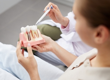 Dentist showing a dental implant model to a patient