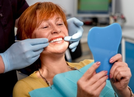 Dental patient admiring her smile in a mirror