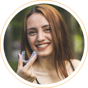 Smiling woman holding Invisalign clear aligner