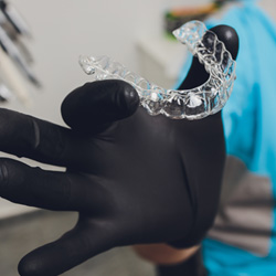 Dentist with black gloves holding Invisalign aligner