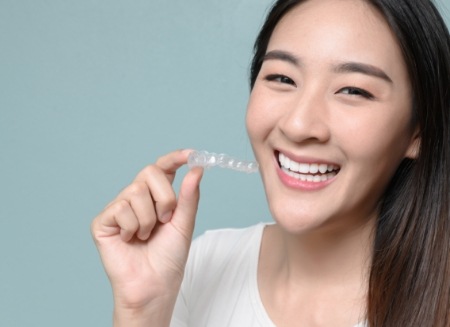 Smiling woman holding Invisalign tray