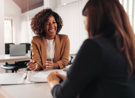 Two women talking while sitting across desk