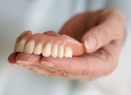 Dentist holding a full denture