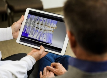 Dentist showing a patient a tablet with digital model of teeth