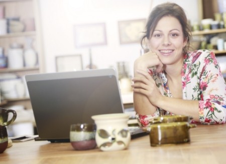 Woman sitting at kitchen table with laptop