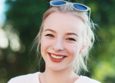 Young blonde woman grinning outdoors