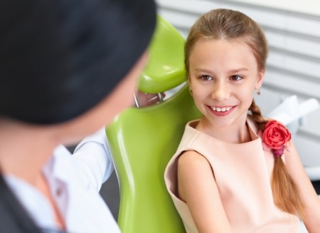 Young girl in dental chair smiling at her dentist