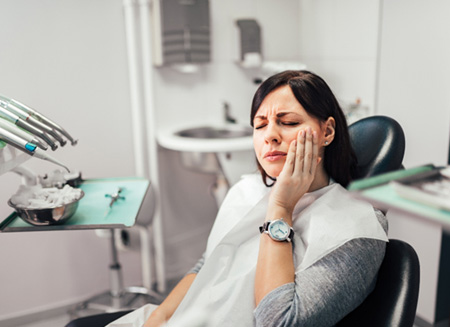 Woman with toothache sitting in treatment chair