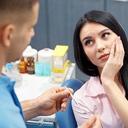 A patient holding her jaw due to a painful toothache