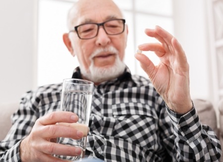 Man holding pill and glass of water