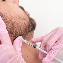 Man receiving injection near his jaw