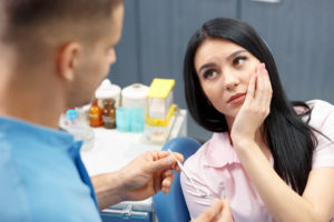 Woman in dental chair holding jaw