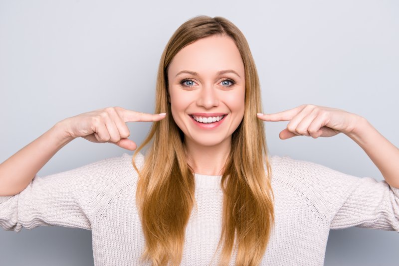 girl smiling pointing to her straight teeth