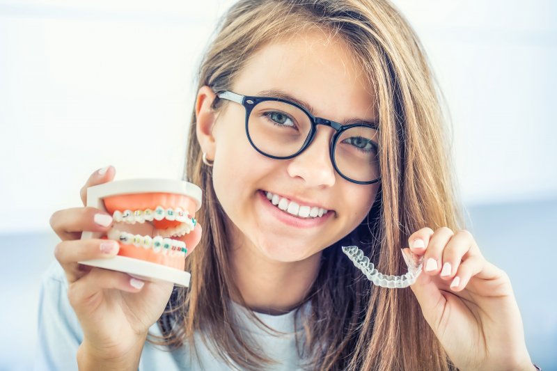 girl holding up braces and Invisalign