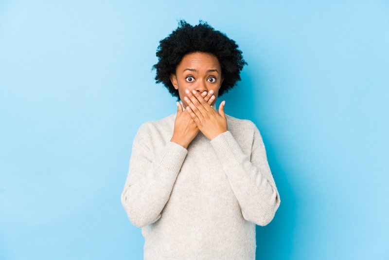 person with bad teeth covering their mouth