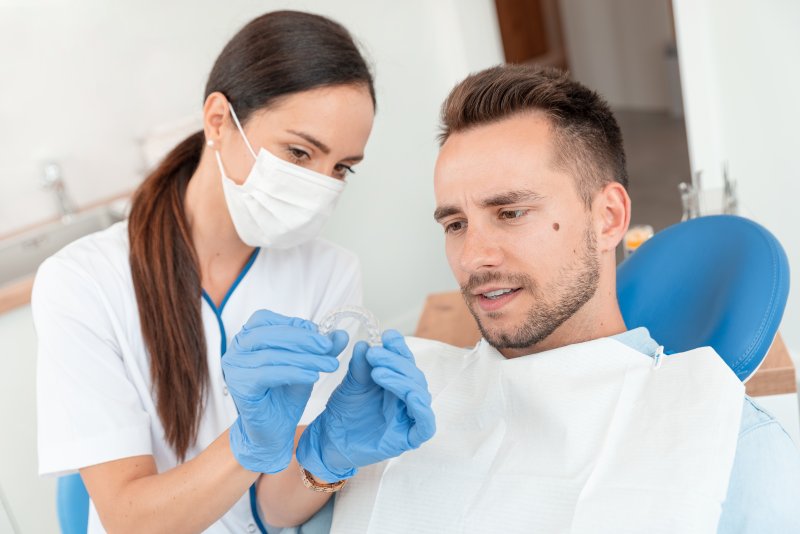 Dentist shows patient an Invisalign aligner tray