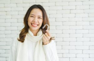a woman smiling and holding her aligner