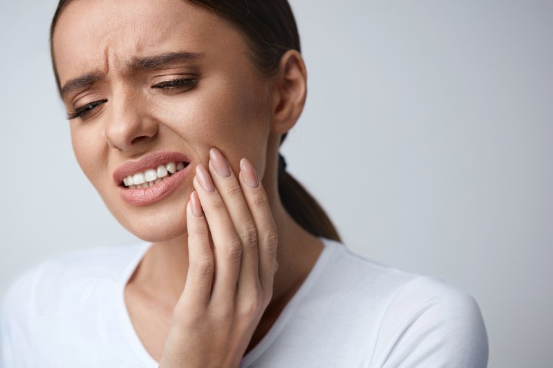 person holding their tooth and wincing in pain