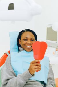 Happy female dental patient looking in mirror