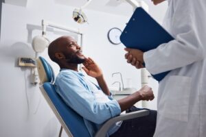 Patient sitting in dentist’s chair talking to dentist.